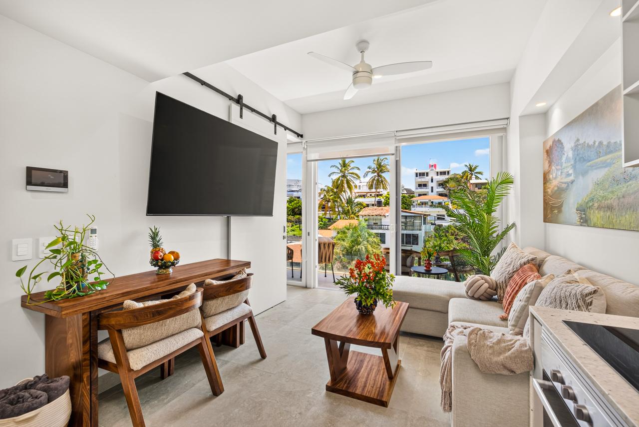 Living room at Casa Nayah with wall-mounted TV, dining console and palm views