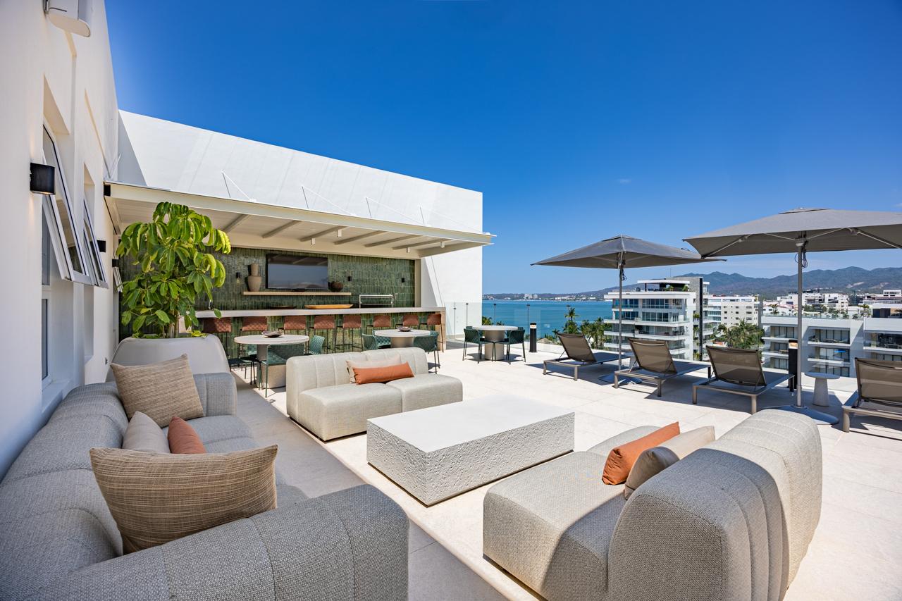 Rooftop lounge with modular sofas, umbrellas, and ocean-facing bar
